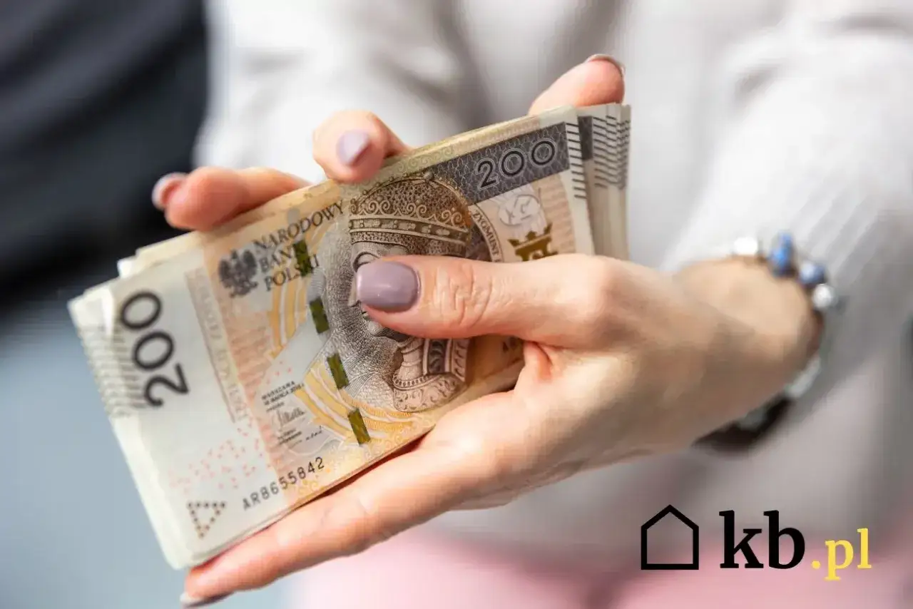 Dłonie trzymające stos banknot&oacute;w 200 zł. Czy oszczędności w got&oacute;wce to dobry pomysł, gdy urząd skarbowy może się nimi zainteresować?