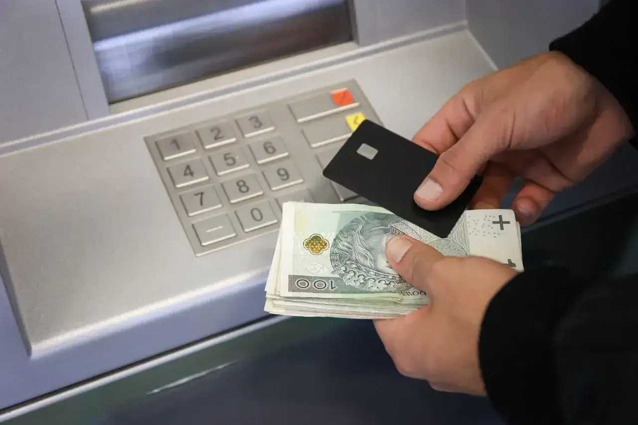 Instrukcja, jak wpłacić pieniądze na konto: trzymaj kartę i got&oacute;wkę przy bankomacie.