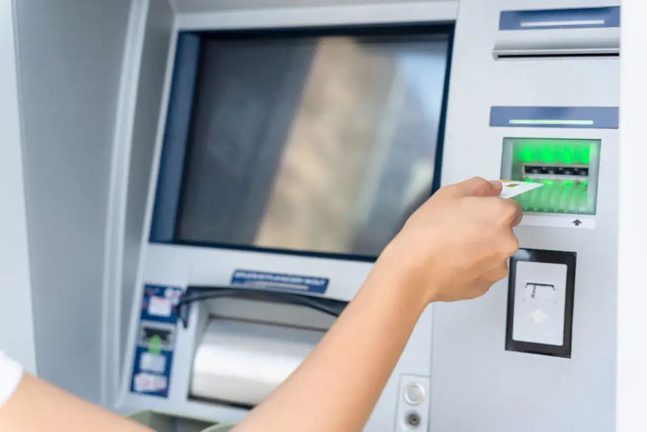 Gdy bankomat wciągnął kartę, jak się załatwia zwrot? Dłoń wkłada kartę do bankomatu.