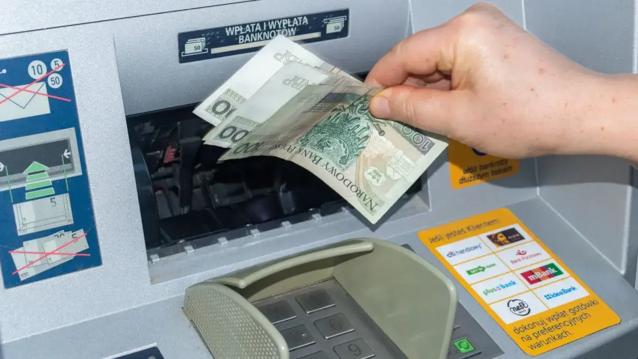 Wpłatomat przyjmuje banknoty 10, 20, 50 i 100 zł. Widać rękę wkładającą polskie banknoty do maszyny.