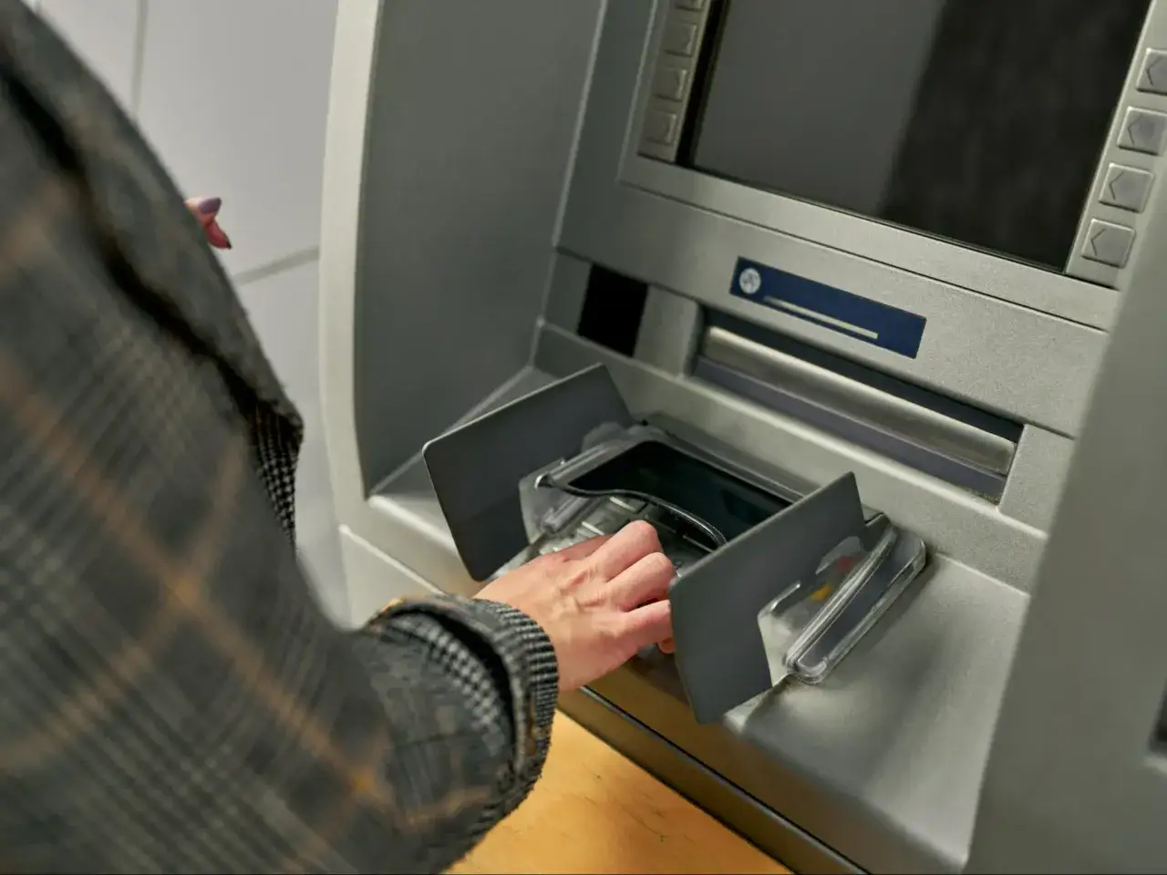 Dłoń pobiera got&oacute;wkę z bankomatu Santander. Limit wypłaty w oddziale może być istotny przy większych transakcjach.