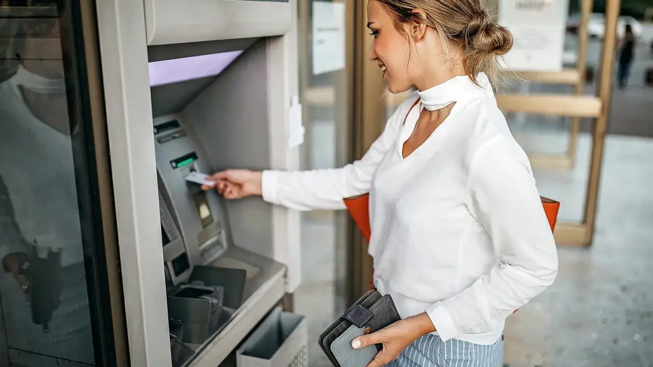 Kobieta wkłada kartę do bankomatu, by dowiedzieć się, jak wypłacić pieniądze z bankomatu za granicą.