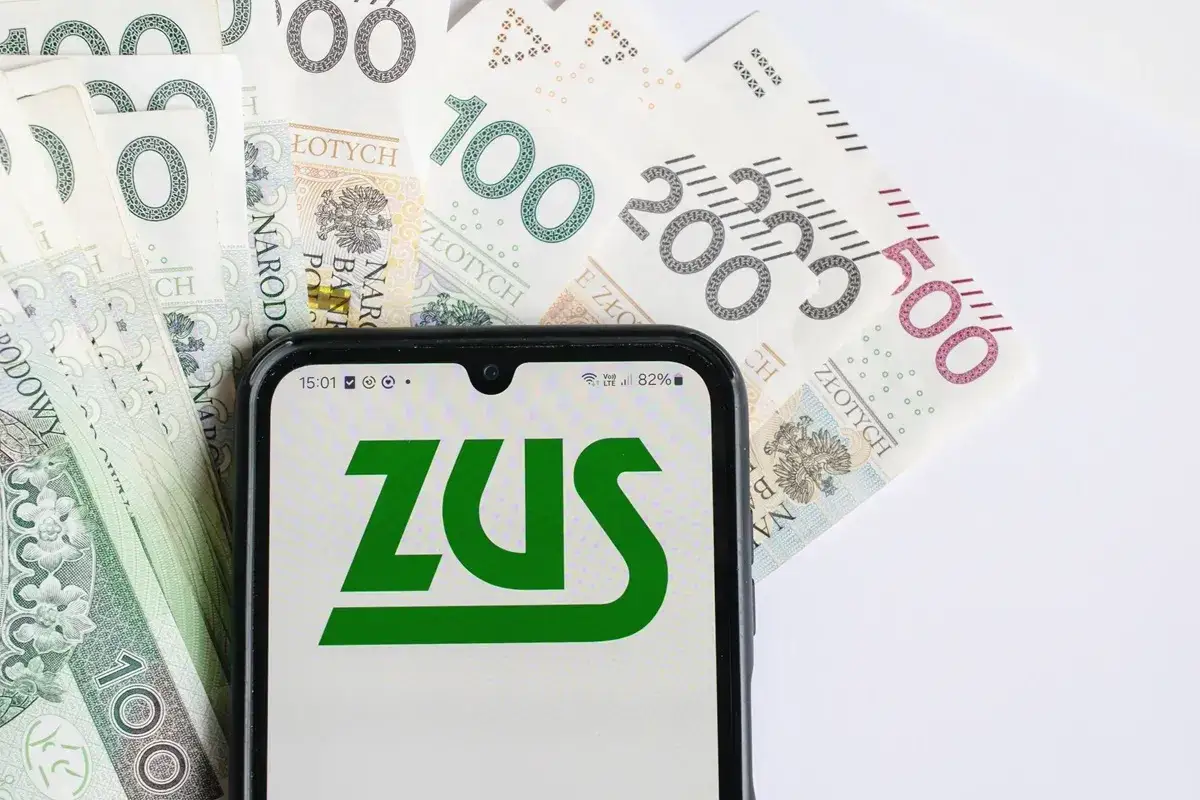 Telefon z logo ZUS na tle polskich banknot&oacute;w. Temat: 14 emerytura po śmierci.