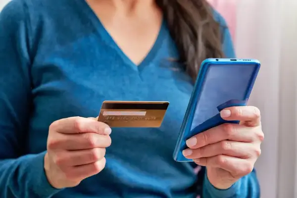 Kobieta trzyma kartę i telefon, planując jak przelać pieniadze z Revoluta.