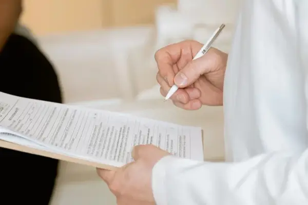 Ręka trzymająca długopis nad dokumentami. Widać fragmenty formularzy, które mogą być związane z Familienkasse druki po polsku.