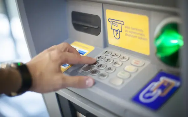 Dłoń wybiera PIN na wpłatomacie bez karty. Wpłata banknotów jest prosta, nawet bez użycia karty.